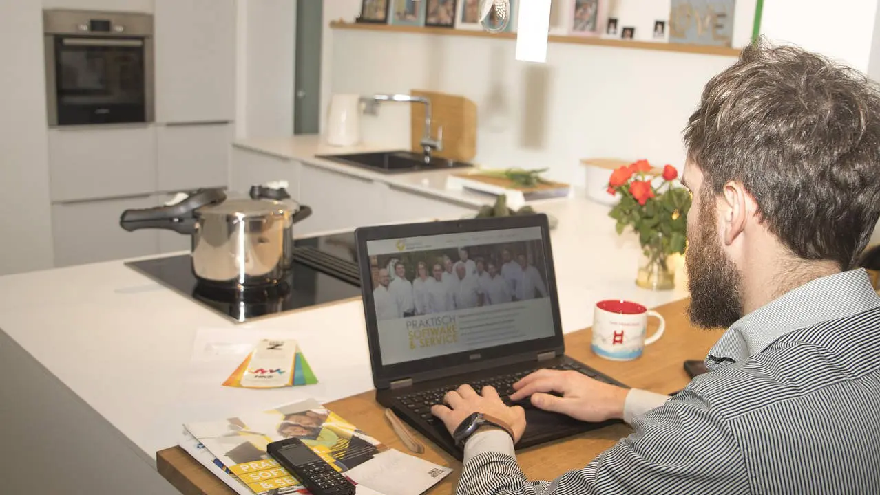 Homeoffice und Schlaf- Ein Mann sitzt in der Küche am Laptop